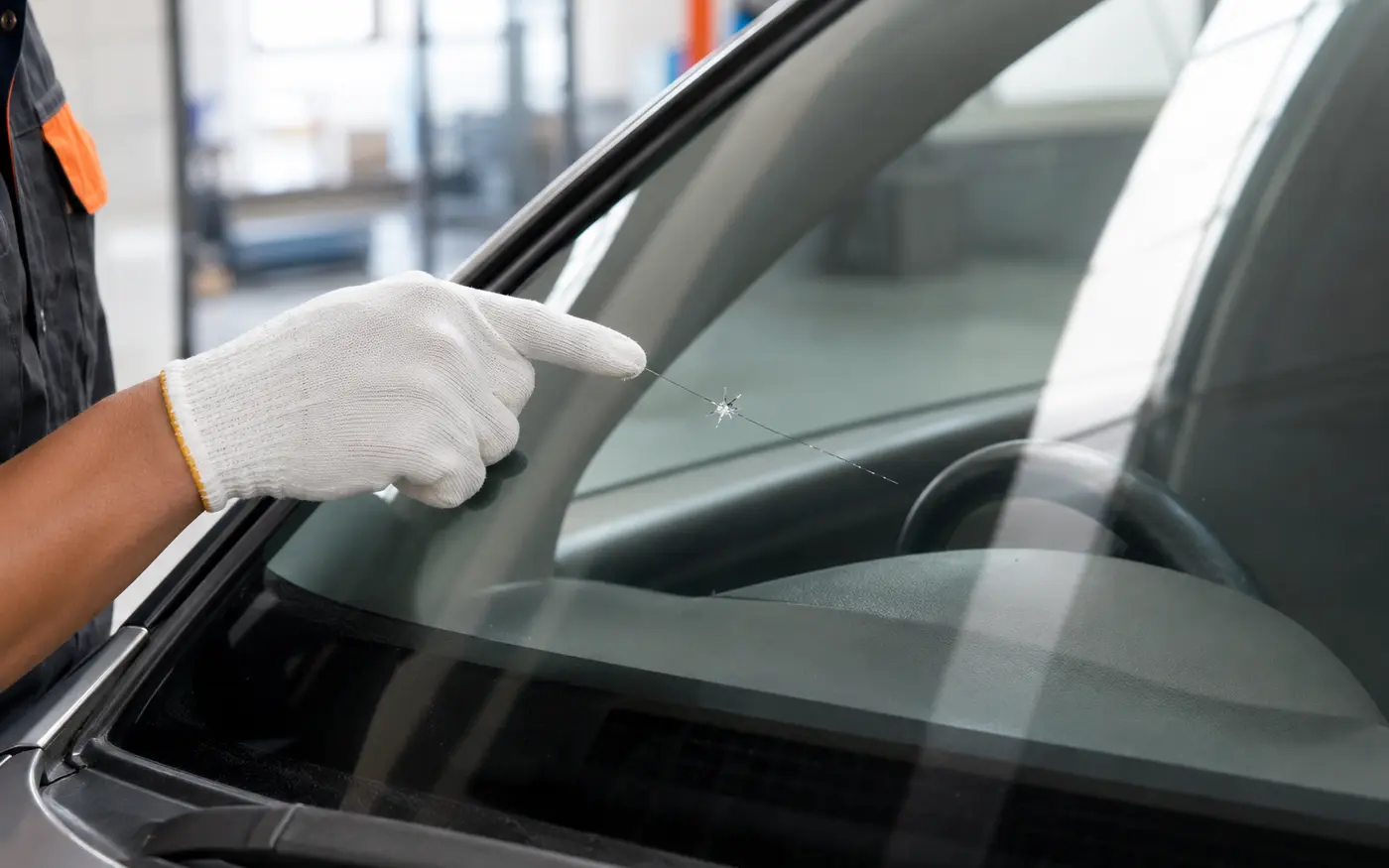 Teknisi memeriksa pola retak pada kaca depan mobil